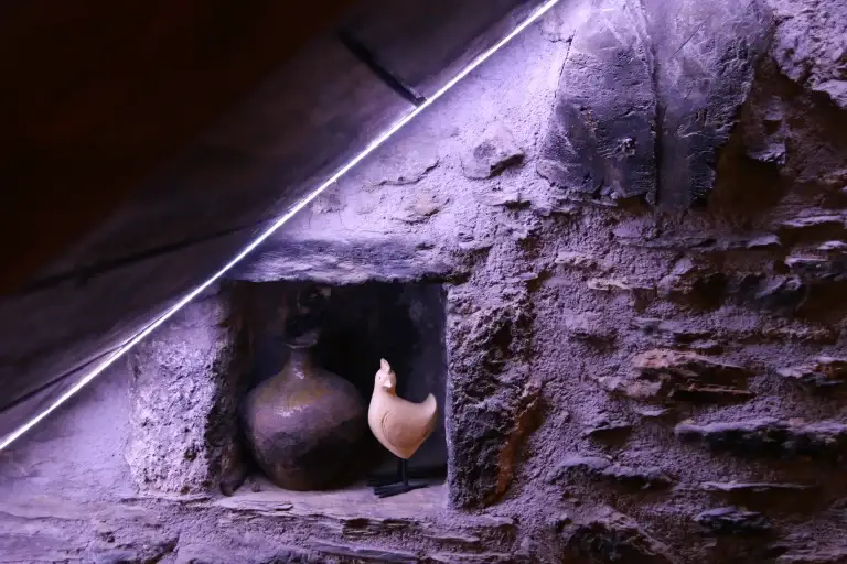 Fornícula a la paret de pedra amb un gerro i una figura decorativa