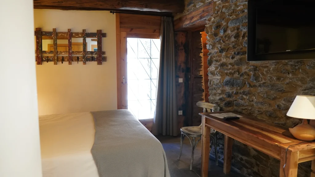 Habitació 1 amb escriptori i paret de pedra