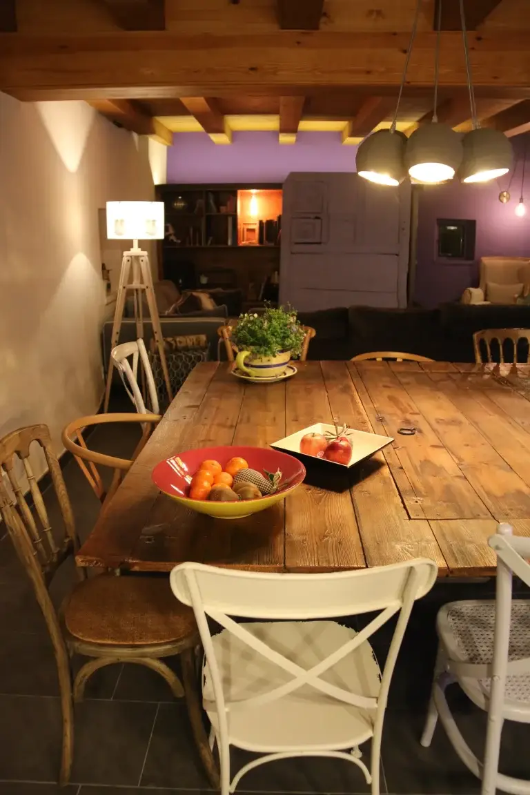 Menjador amb taula de fusta i la sala d'estar al fons