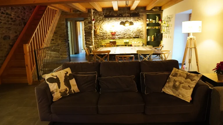 Sala d'estar amb sofà i menjador al fons a Cal Batlle
