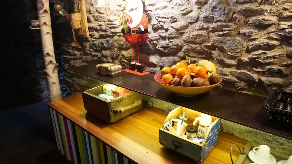 Taulell amb fruita i infusions davant la paret de pedra