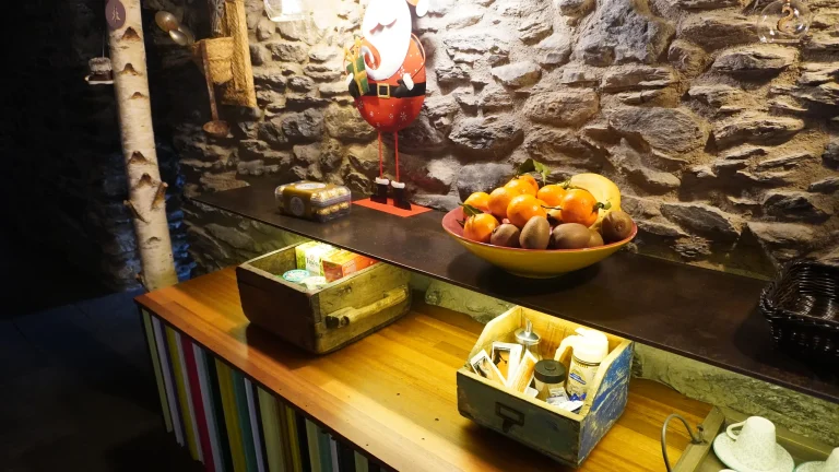 Taulell amb fruita i infusions davant la paret de pedra